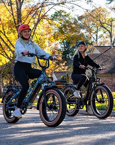 Two riders enjoying electric bikes on a sunny autumn path